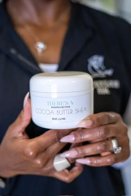 Theresa holding a jar of cocoa butter body care